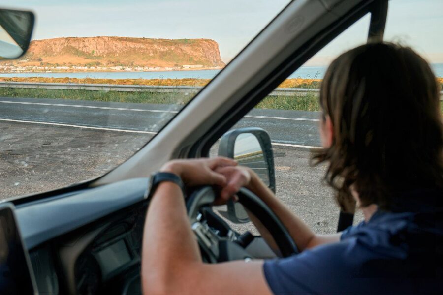 De bestuurder heeft de Apollo Euro Mini camper naast de weg geparkeerd en bekijkt de kustlijn van Tasmanië
