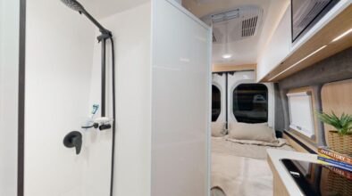 Deur open van de badkamer in de Cruisin' Rover camper met zicht op het bed