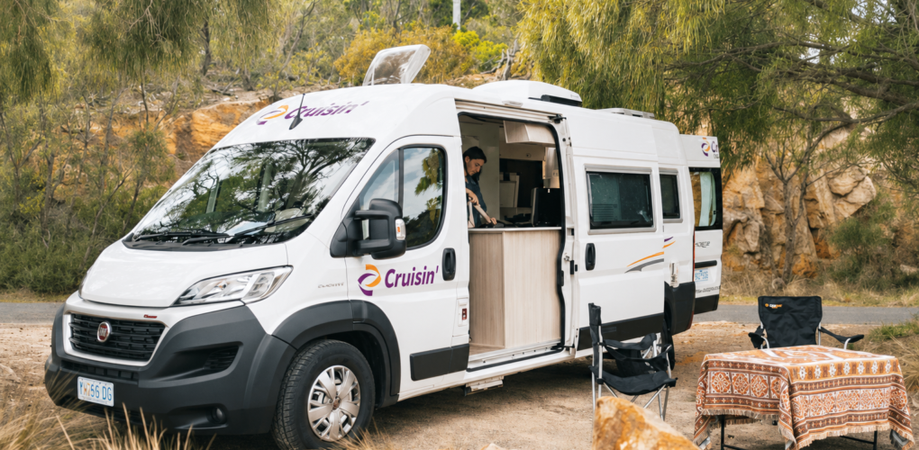Zijaanzicht van de Cruisin' Sandpiper camper, vrouw staat in keuken binnen