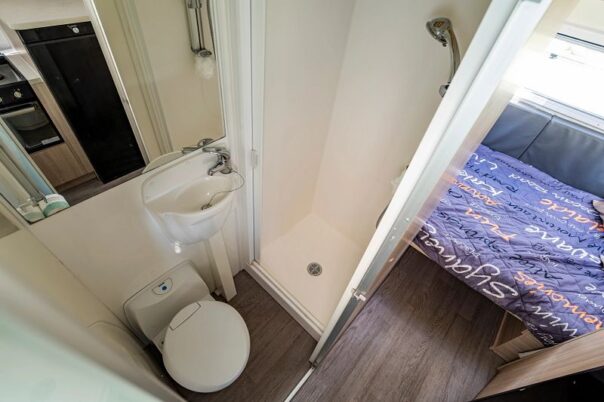 Badkamer met toilet en wastafel met deur open in de Mighty Big Six camper