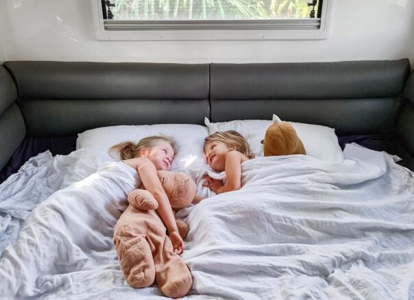 Kinderen liggen met knuffels in bed in Maui Beach camper en zijn nog wakker