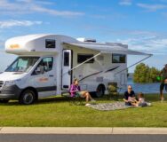 Vader speelt plakbal en moeder leest boekje met kind op kleed voor de Apollo Euro Deluxe camper