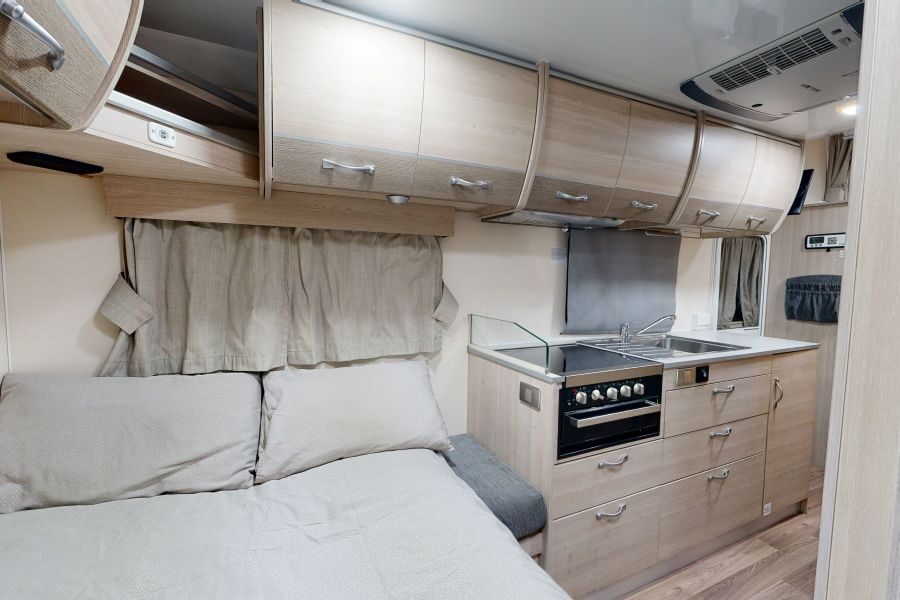 Het bed achter in de Go Cheap Henty is opgemaakt, met zicht op de keuken