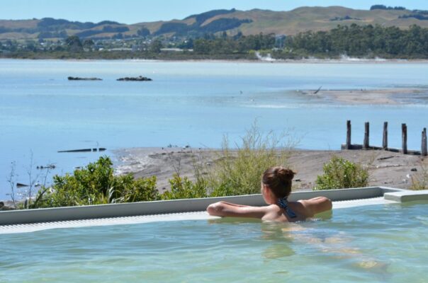 Jonge vrouw ligt in spa in Rotorua over het meer te kijken