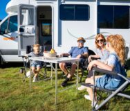 Gezin met jonge kinderen zit in campingset voor Apollo Euro Quest camper