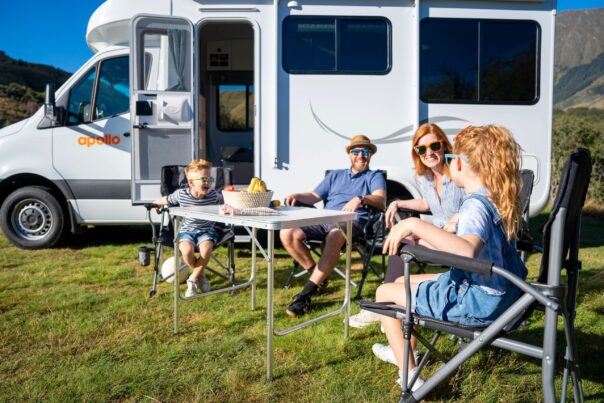 Gezin met jonge kinderen zit in campingset voor Apollo Euro Quest camper
