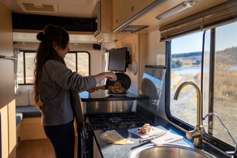 Een vrouw is aan het koken in de keuken van de Star RV Polaris 6