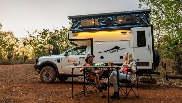 Man en vrouw zitten in de schemer voor de Britz Maverick camper in de Northern Territory