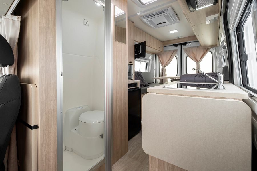 Inkijk in de Britz Trailblazer van voor naar achter met toilet keukenblok en zithoek achterin