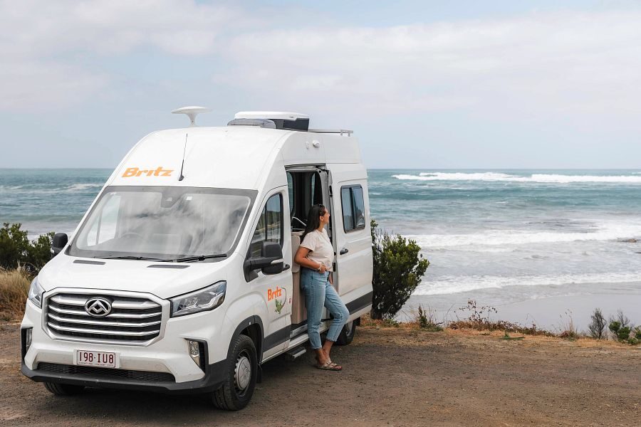 Britz Trailblazer Australië voorkant camper met open zijdeur waar vrouw staat met uitzicht op zee