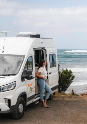 Britz Trailblazer Australië voorkant camper met open zijdeur waar vrouw staat met uitzicht op zee