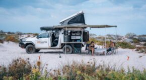 De reizigers hebben een prachtige locatie gevonden om te kamperen bij Coral Bay - West Australië - met zicht op de zijkant van de RedSands camper en opengeklapte daktent