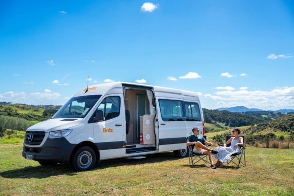 Een koppel zit in campingstoelen voor de Britz Venturer in een grasveld in Nieuw-Zeeland tijdens hun camperreis