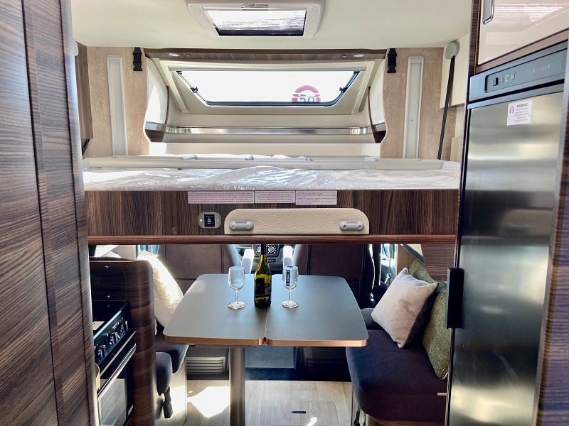 Het drop down tweepersoonsbed is naar beneden boven de zithoek voorin de Britz Odyssey camper in Nieuw-Zeeland