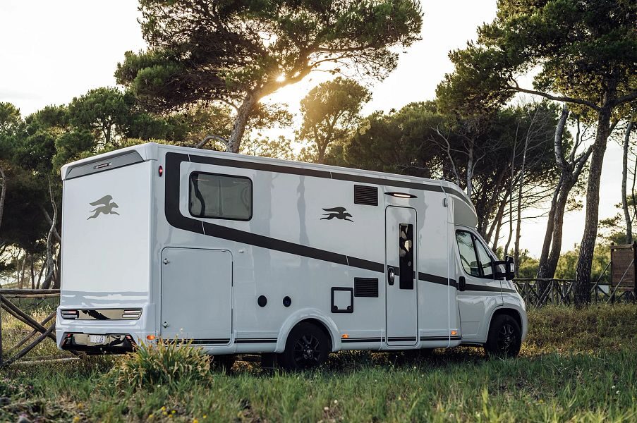 De zij- en achterkant van de in het gras geparkeerde Britz Odyssey camper in Nieuw-Zeeland