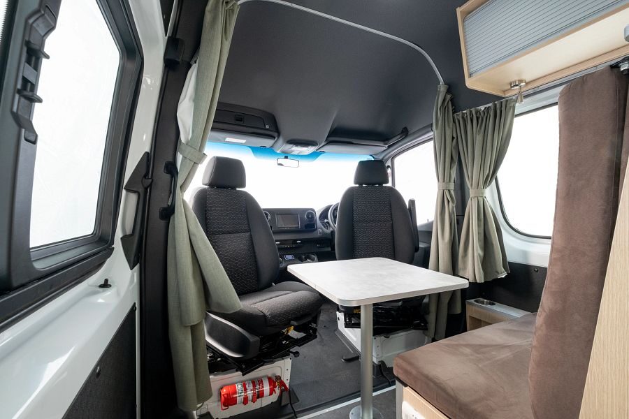 Voorin de Maui Ultima Plus camper is een zithoek met tafel waarbij de bestuurdersstoelen in de cabine draaibaar zijn