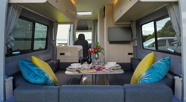 De tafel van de zithoek achterin de Wendekreisen Koru Star 2 Freedom VW is gedekt en er is zicht op het interieur vanuit de open achterdeuren