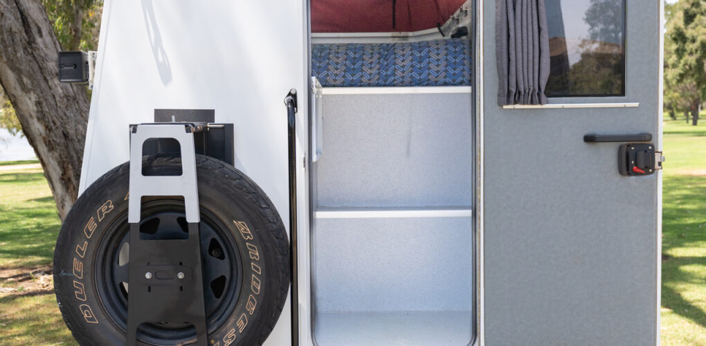 De achterzijde van de camper is toegankelijk via een deur en een uitklapbaar trapje. Daarnaast is een reservewiel bevestigd en het dak omhoog gezet