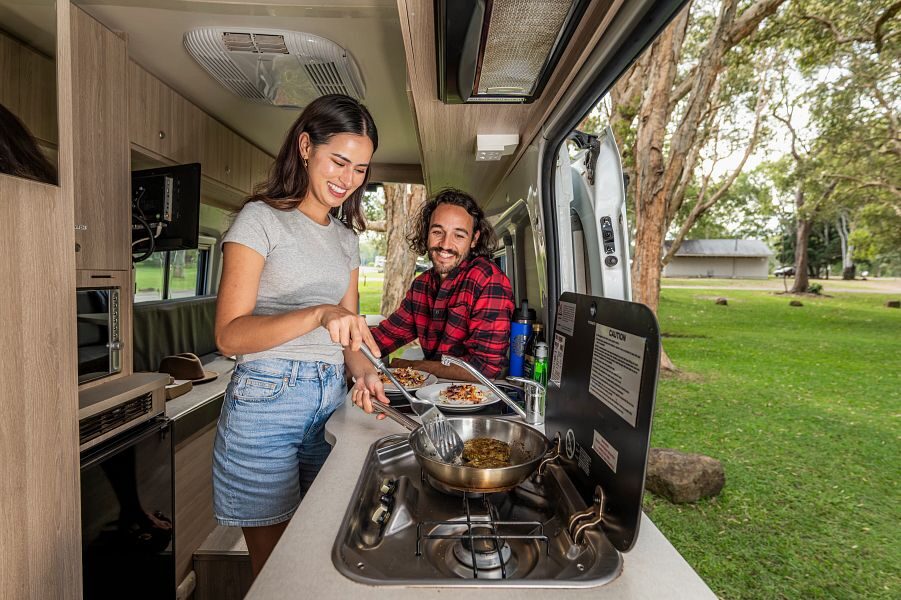Een koppel is aan het koken in de keuken van de Mighty Highball camper