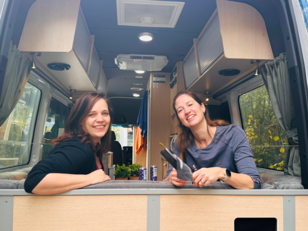 Carolien en Leonore van het administratie team van Campers Down Under zitten in de camper met de achterdeur open