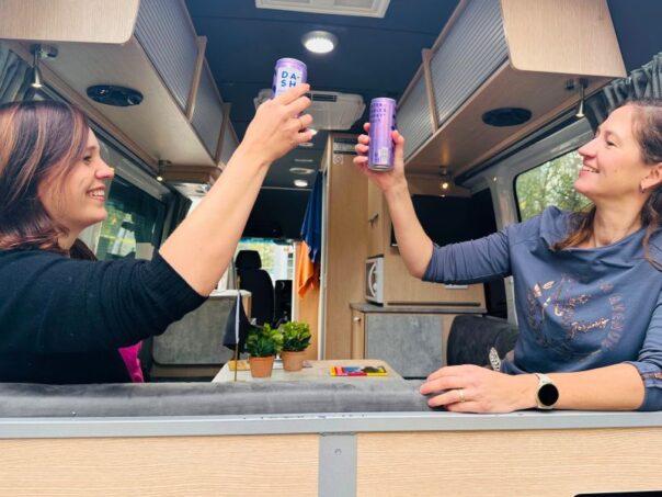 Carolien en Leonore van Campers Down Under proosten in de Maui Ultima met de achterdeur open