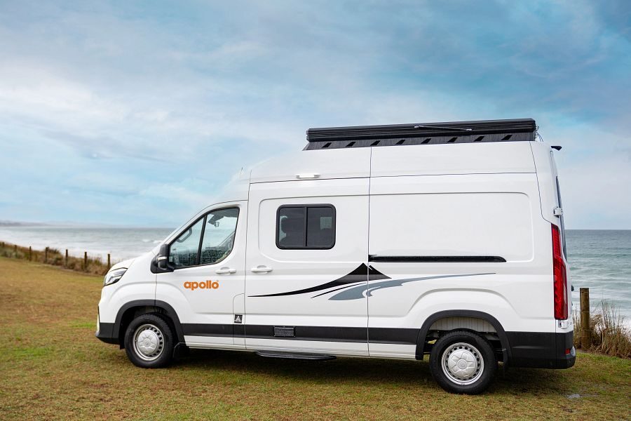 De Apollo Hitop camper staat geparkeerd in het gras aan zee vanaf de zijkant gezien in Australië