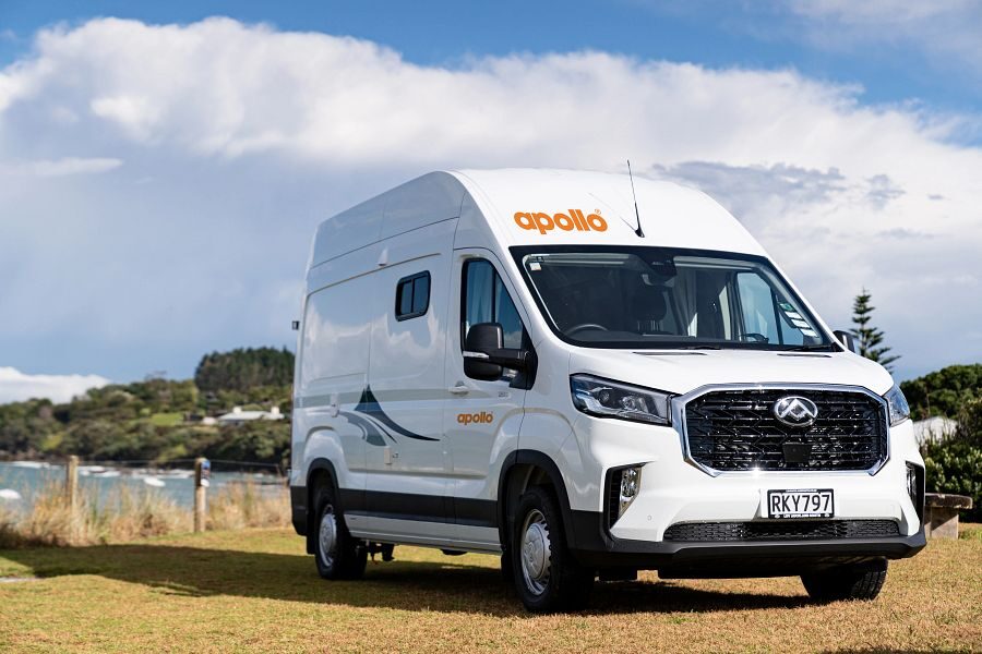 De Apollo Hitop camper staat geparkeerd op het gras langs het water in Nieuw-Zeeland