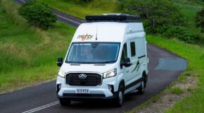 Een vrouw rijdt in de Mighty Double Down camper met daktent over een slingerende asfalt weg