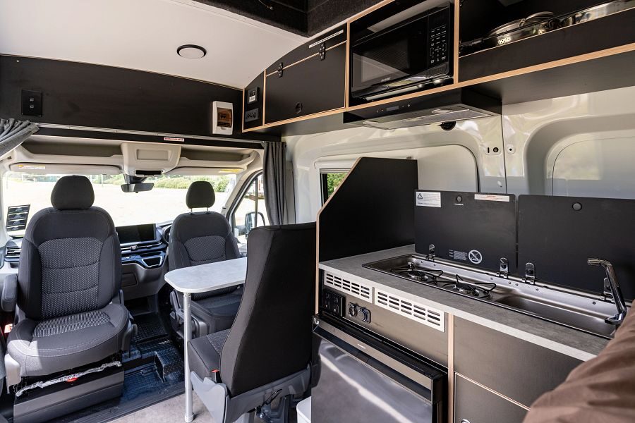 Het interieur van de Mighty Double Down camper in Australië en Nieuw-Zeeland met een keuken en twee draaibare bestuurderstoelen zodat er een zithoek voorin de camper is