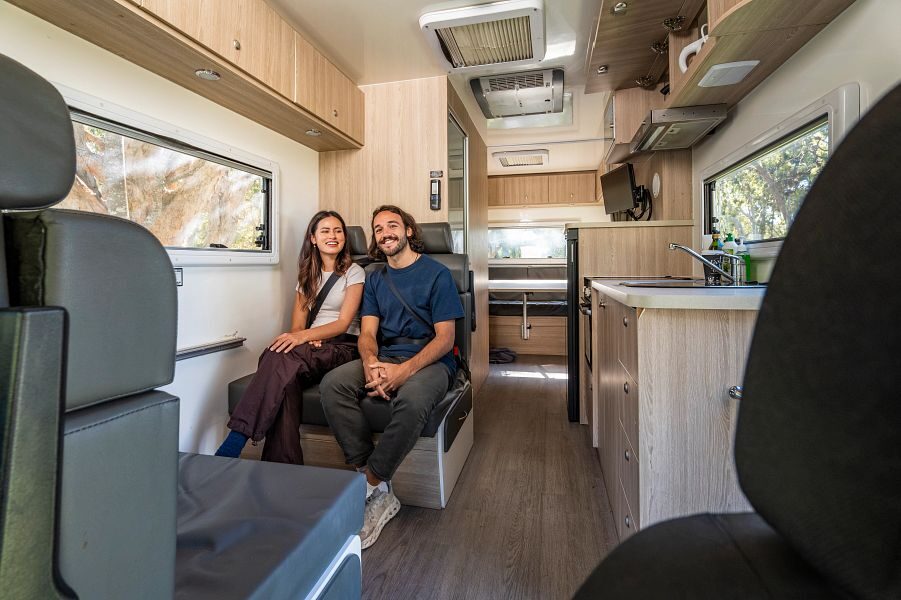 Een koppel zit met hun gordels om op de zitplaatsen achter de cabine van de Mighty Double Up camper