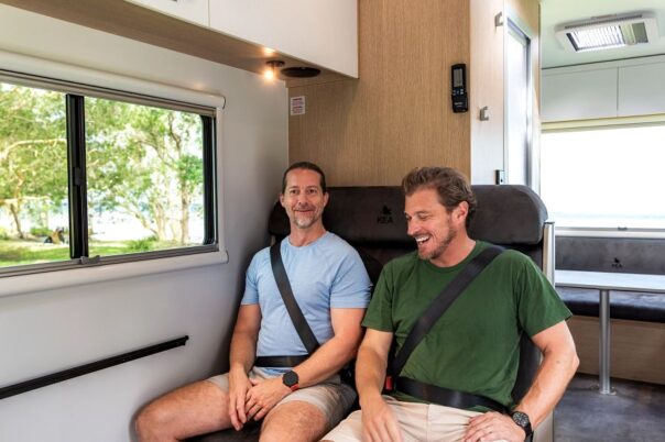 Twee mannen zitten in de gordels in de bank in de dinette van de camper