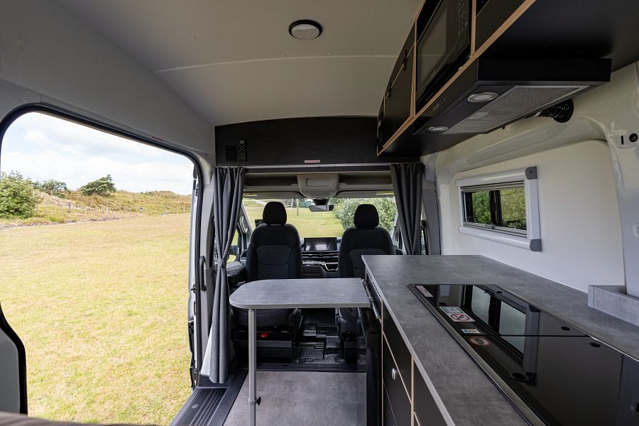 Het interieur en de keuken met uitklapbare tafel en de zijdeur open van de Mighty Lite HiLITE camper in Nieuw-Zeeland