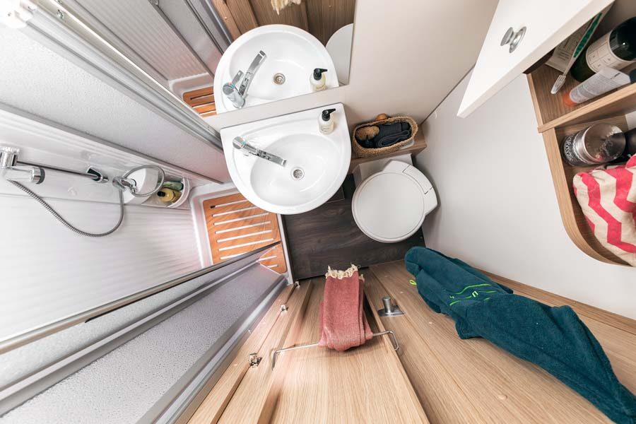 De badkamer van bovenaf gezien met toilet, wasbak en douche in de McRent Family Plus