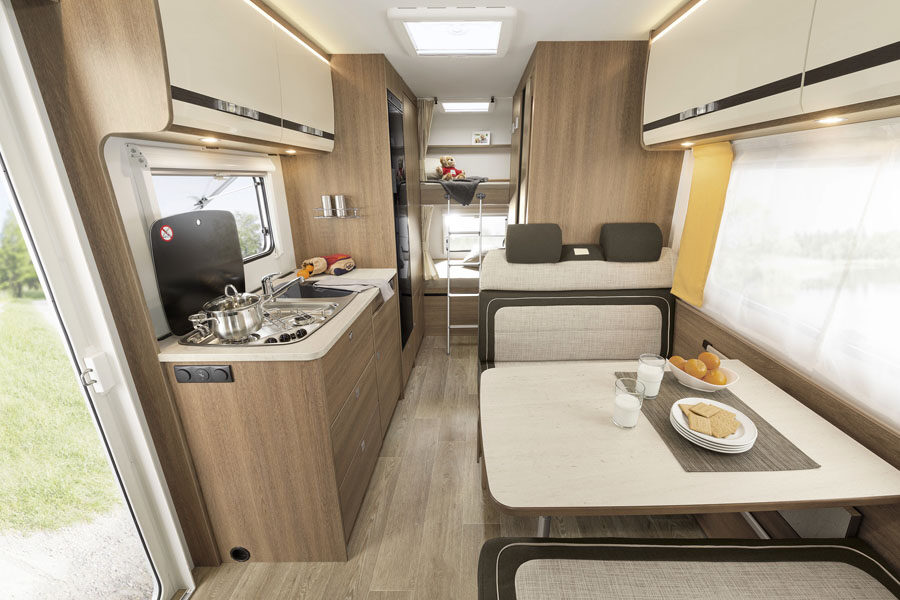 Het interieur van de McRent Family Plus camper van voor naar achter met zitgedeelte, keuken, badkamer en stapelbed achterin