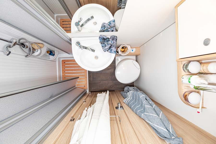 De badkamer met douche, wasbak en toilet van de McRent Family Luxury van bovenaf gezien