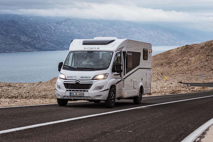 Een stel rijdt in de McRent Compact Plus camper over een geasfalteerde bergweg in Nieuw-Zeeland