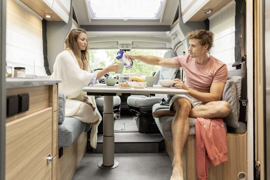 Een stel zit in de zithoek te ontbijten in de McRent Comfort Standard