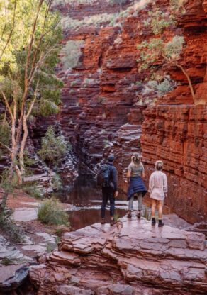Drie mensen staan te kijken in een kloof in Karijini National Park