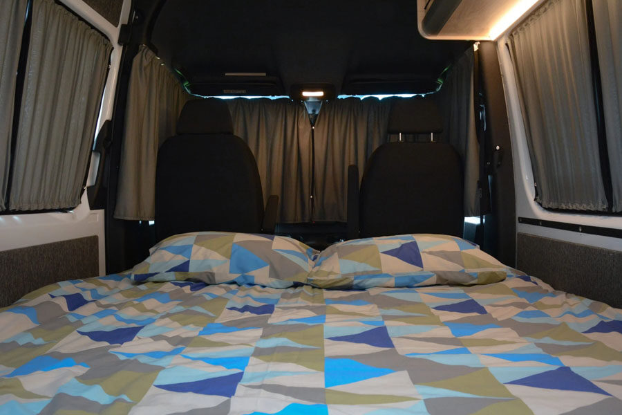 Een opgemaakt tweepersoonsbed in de Pacific Horizon 2 plus 1 camper
