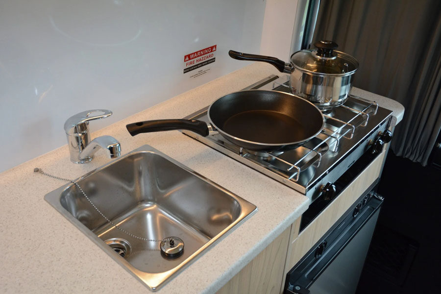 Het keukenblok met wasbak en gasfornuis met twee pannen in de Pacific Horizon 2 plus 1 camper