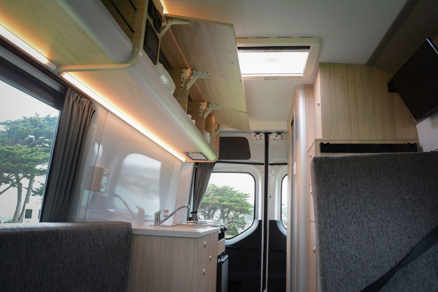 Het interieur met keuken en openstaande bovenkasten in de Pacific Horizon 2 plus 1 camper