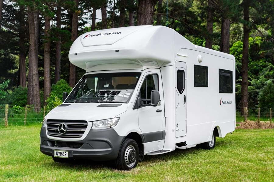 De voor- en zijkant van de Pacific Horizon Gem 4 camper geparkeerd op een grasveld in Nieuw-Zeeland