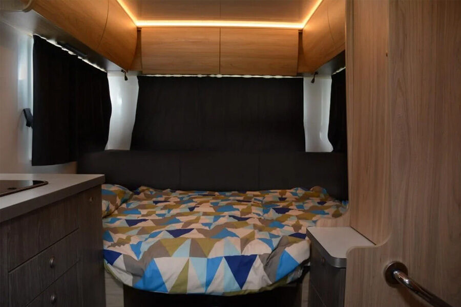 Het tweepersoonsbed achterin met de gordijnen dicht in de Pacific Horizon Max 4 camper
