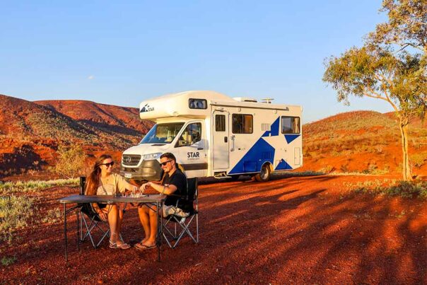 Een koppel zit aan de campingtafel voor de Polaris 6 in de outback van Australië