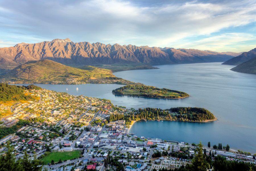 Uitzicht van bovenaf op Queenstown en Lake Wakatipu omringd door hoge bergen