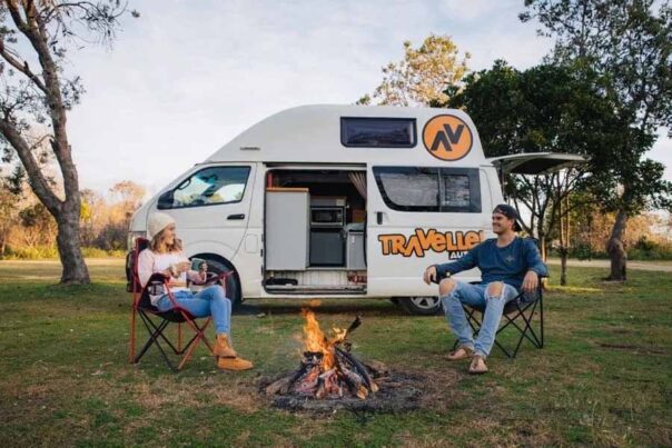 Een stel zit op de campingstoelen bij een kampvuur voor de Travellers Autobarn Kuga camper