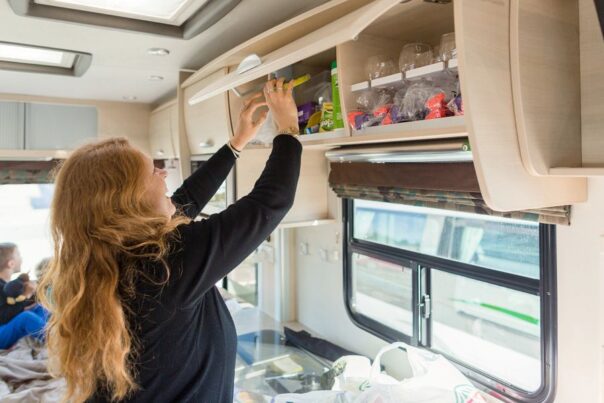 Vrouw bergt boodschappen op in een bovenkast in de keuken van de camper