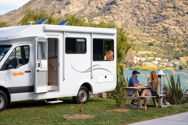 Gezin kampeert met een Apollo camper in Queenstown, kinderen hangen uit het raam
