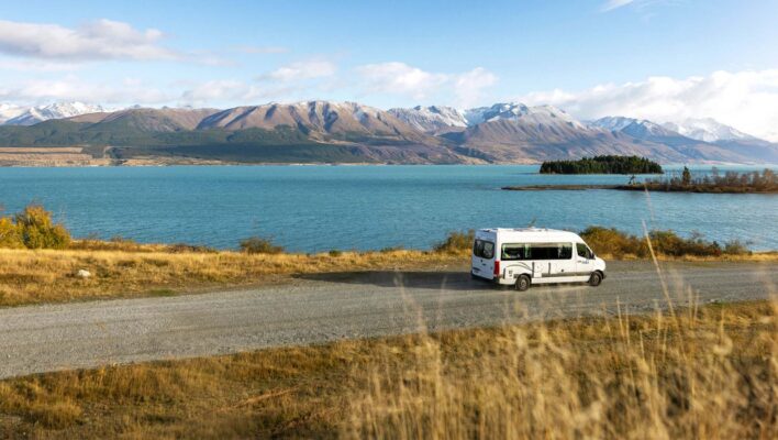 De Maui Ultima rijdt over een weg langs Lake Wanaka met uitzicht op de bergen