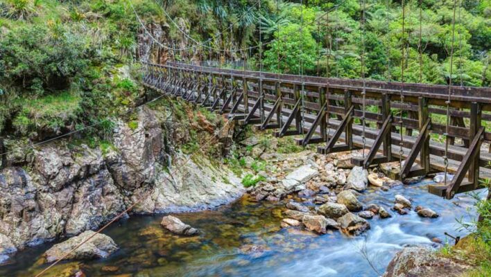 Een houten hangbrug over in een rivier in de Karangahake Gorge